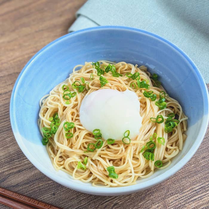 器に盛られたそうめん、トッピングに半熟卵と小ねぎが添えられている。