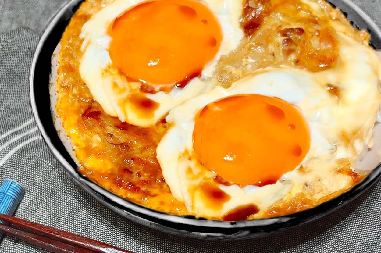 料理が盛られた器には、焼いた卵が2つ載っています。テーブルには箸が置かれています。