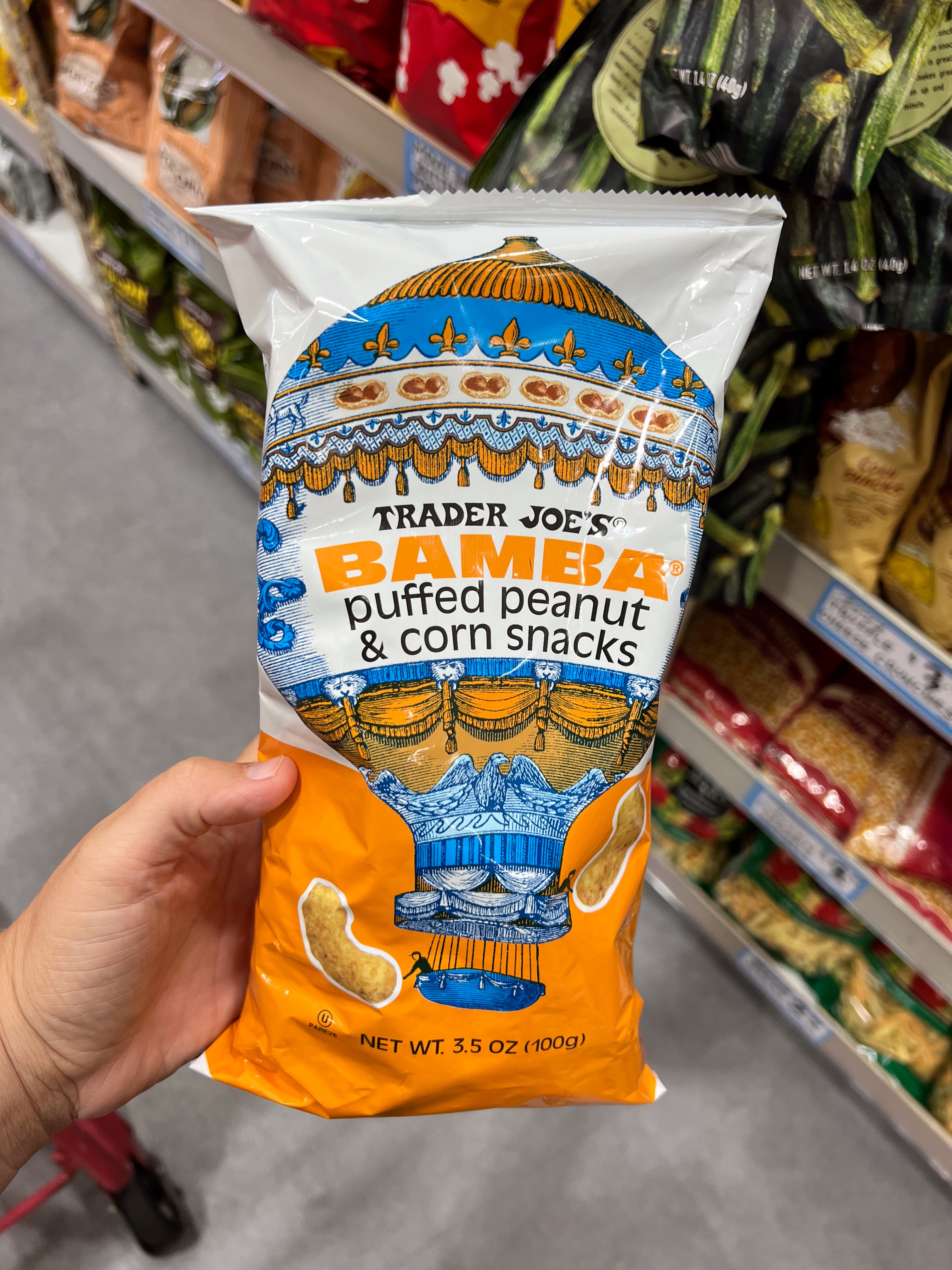 Bag of Trader Joe's Bamba Puffed Peanut & Corn Snacks held in a hand, in a grocery aisle