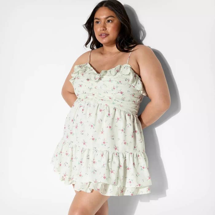 Person poses successful a ruffled, floral, sleeveless formal suitable for casual outings, hands mildly resting connected hips