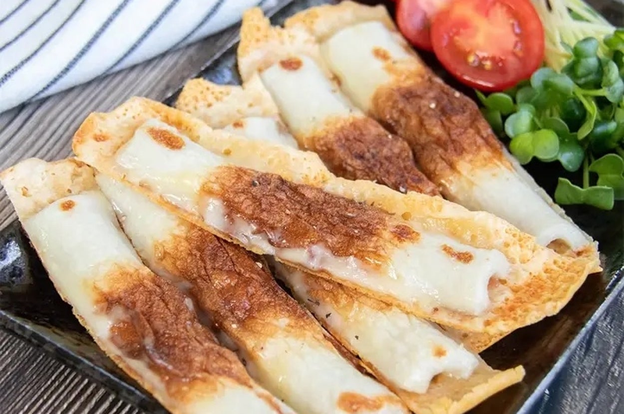 焼き餃子に似た料理が皿に盛られ、トマトと緑の野菜が添えられている。