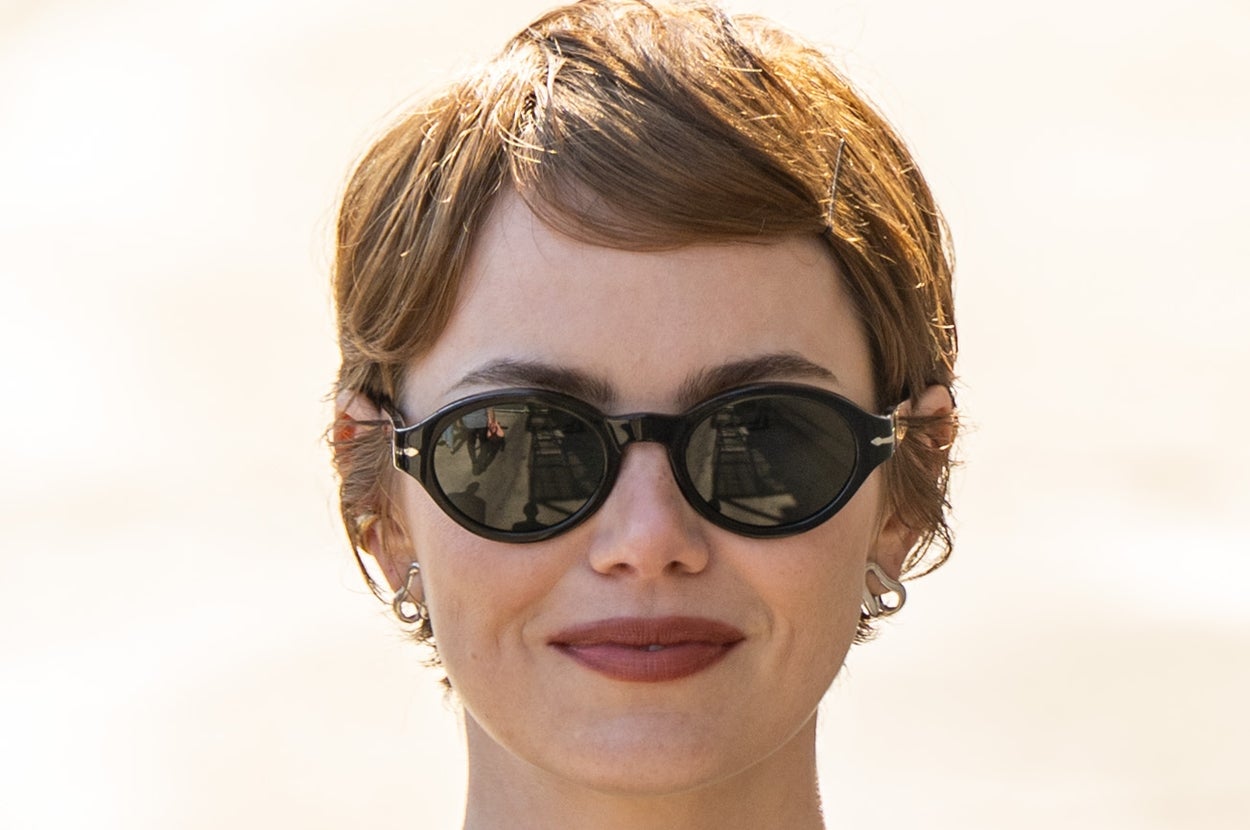 Person with short hair and sunglasses wears a simple, fitted black shirt outdoors