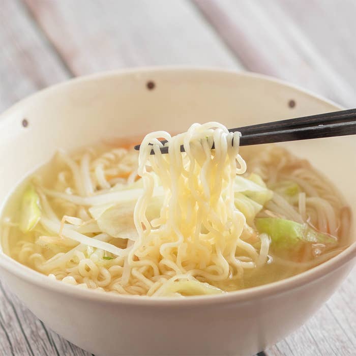 器に盛られたラーメンの上を箸で持ち上げているシーン。白菜と麺が見える。