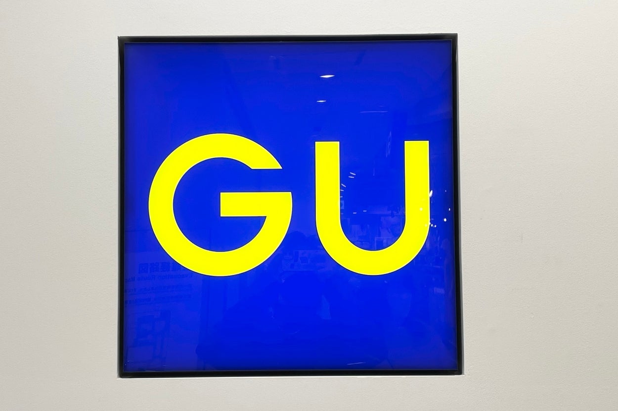 Sign displaying the letters "GU" in bold text, set against a contrasting background within a square frame
