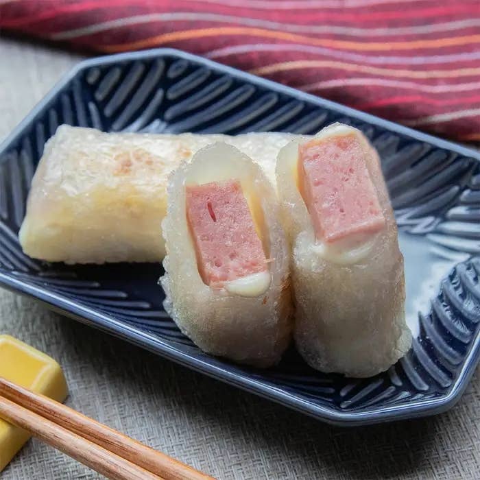 お皿に盛られたカットされたスパムとチーズ入りのライスペーパー料理。箸が添えられている。