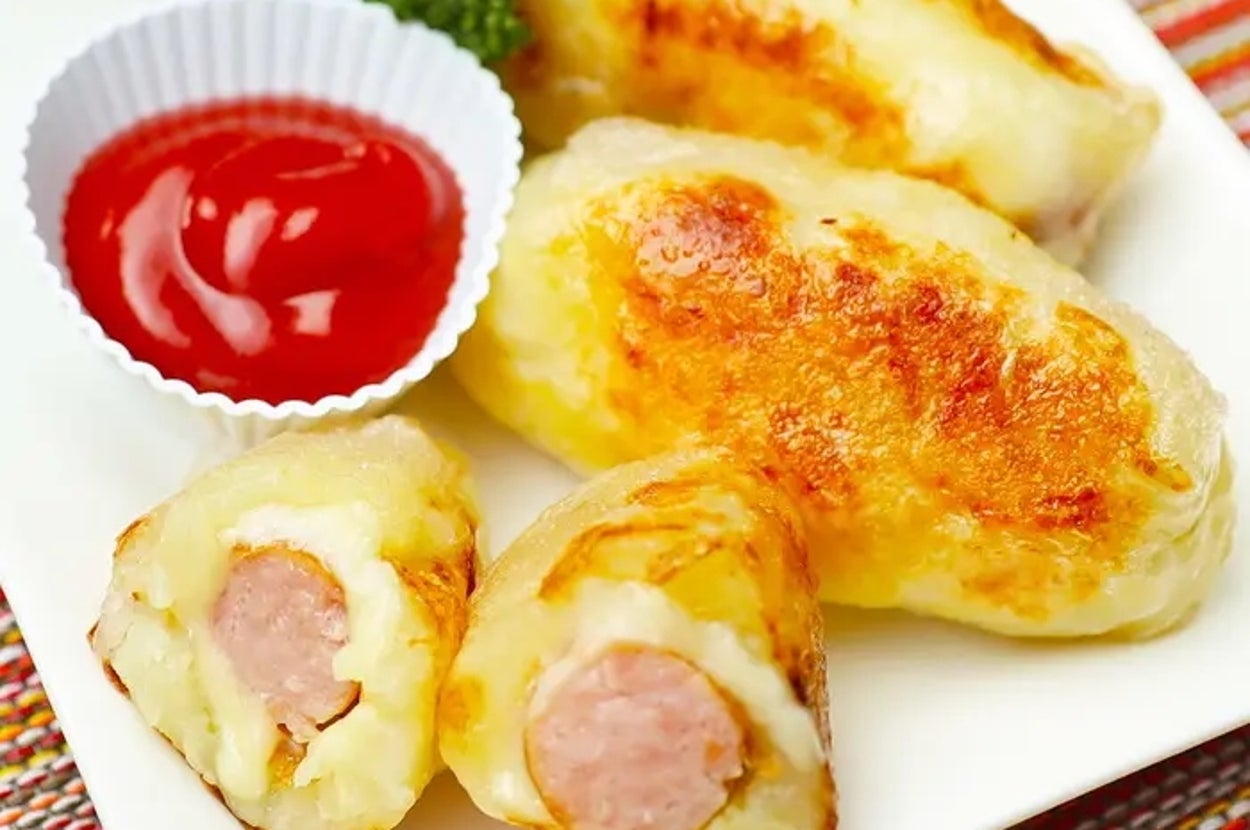 プレート上にケチャップとパセリを添えたポテトで包んだソーセージ。レシピ広告用のイメージ。