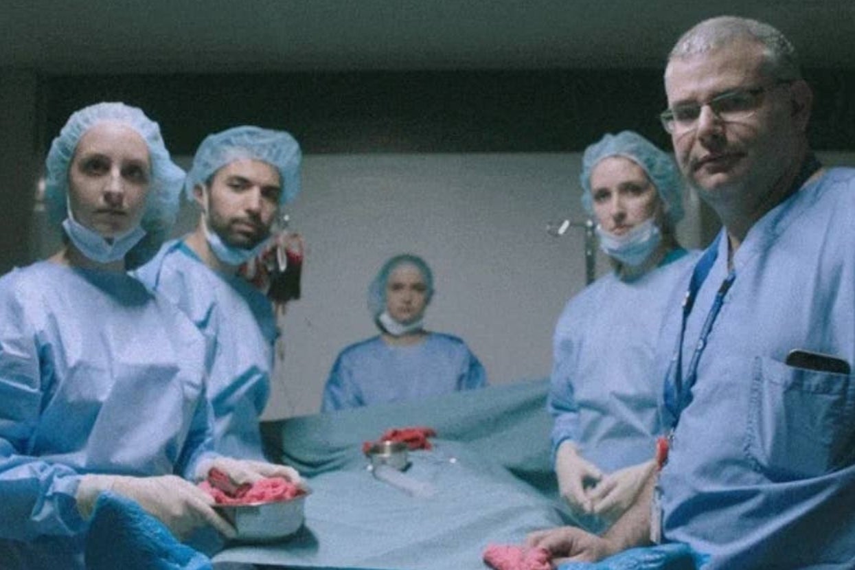 Medical team in surgical scrubs surrounding an operating table, focused and attentive