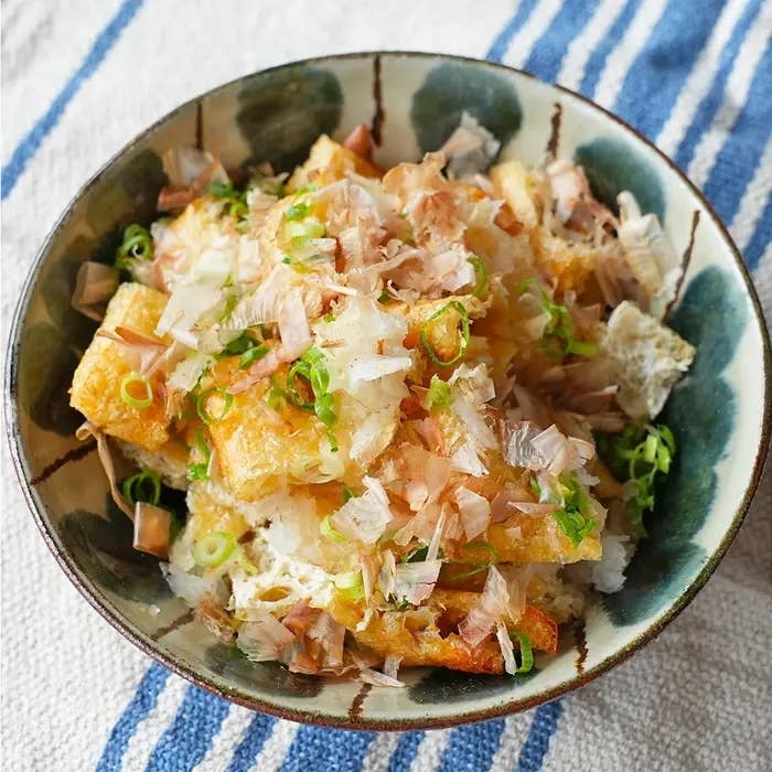 鰹節やネギがトッピングされた料理が、模様のある器に盛られている。