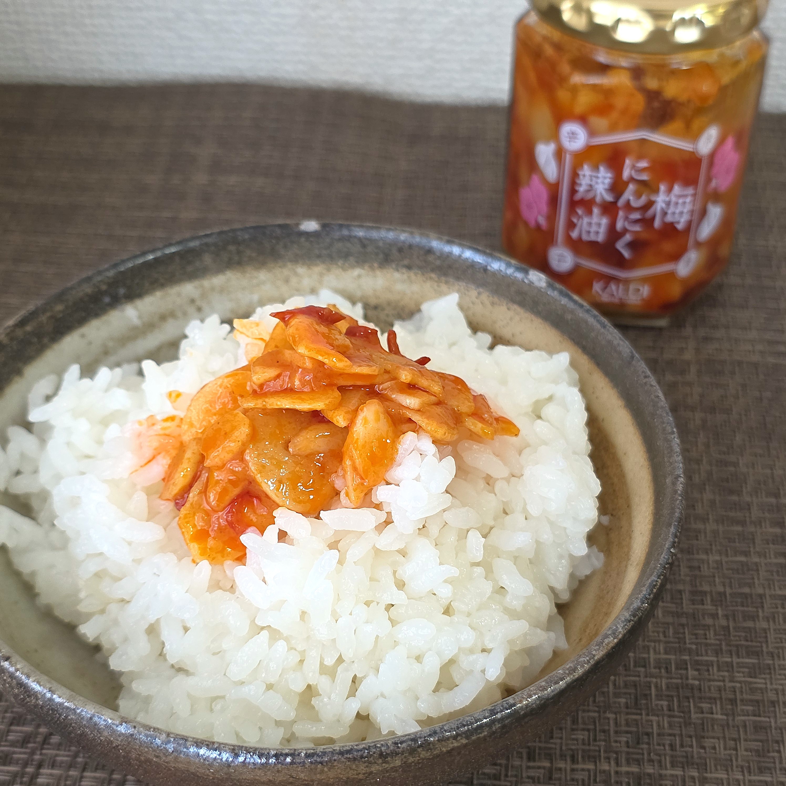 白いご飯に梅にんにく辣油がトッピングされたボウルと、梅にんにく辣油の瓶。