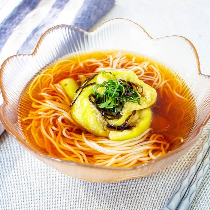 ガラスの器に盛られたラーメン。上には野菜と海藻がトッピングされている。