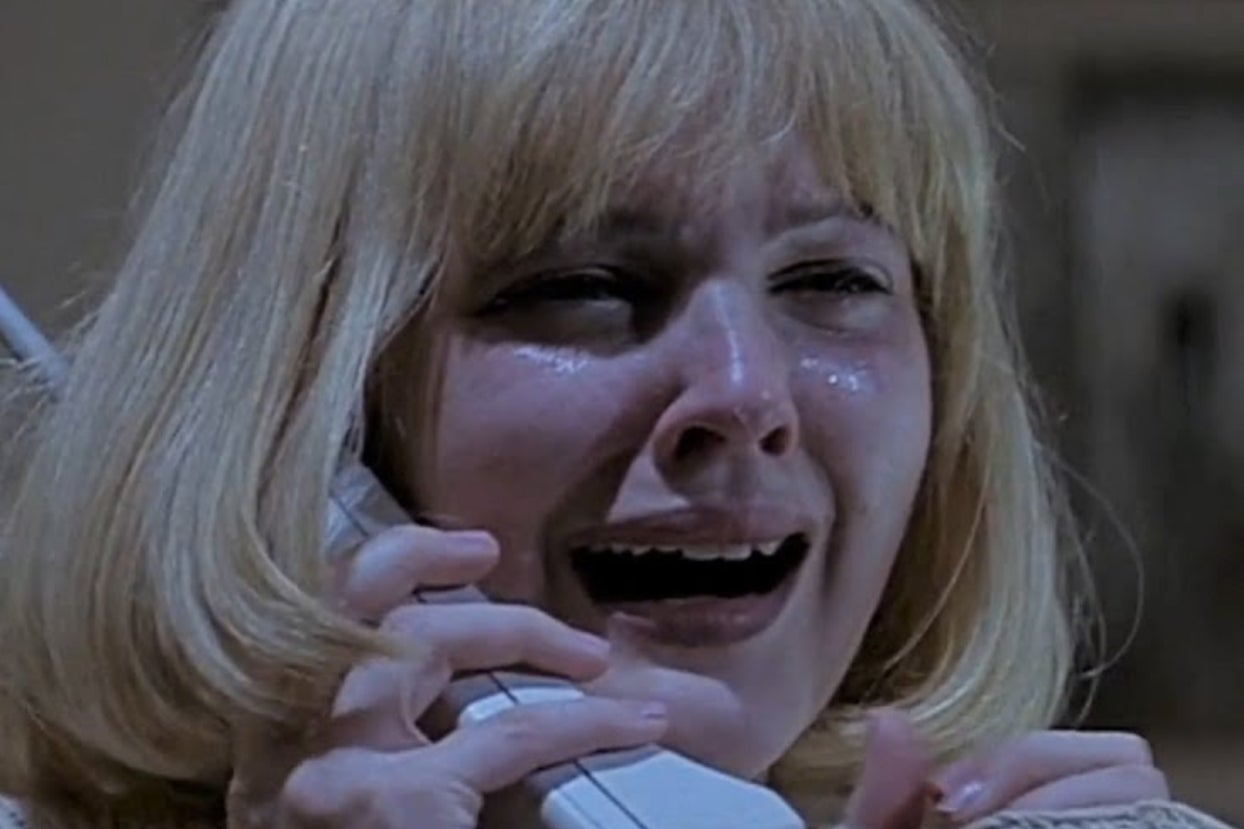 Person with blonde hair appears distressed while holding a phone to their ear, mouth open as if speaking or shouting