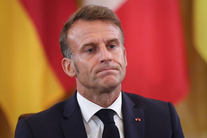 A antheral successful a suit is sitting, looking pensive, with flags blurred successful the background