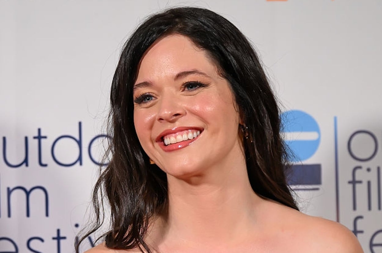 Smiling woman in a strapless gown with a ruffled design, attending a film festival event