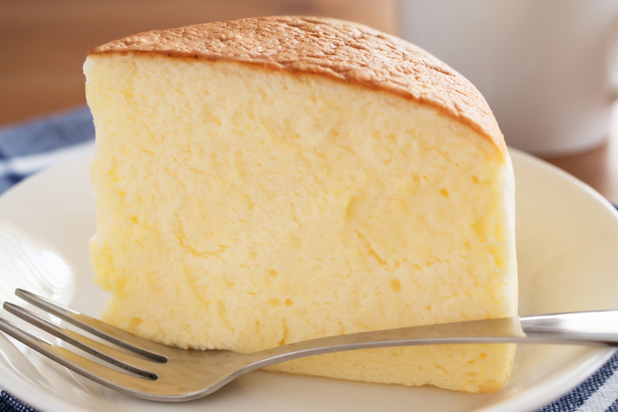A slice of fluffy cheesecake on a plate with a fork beside it