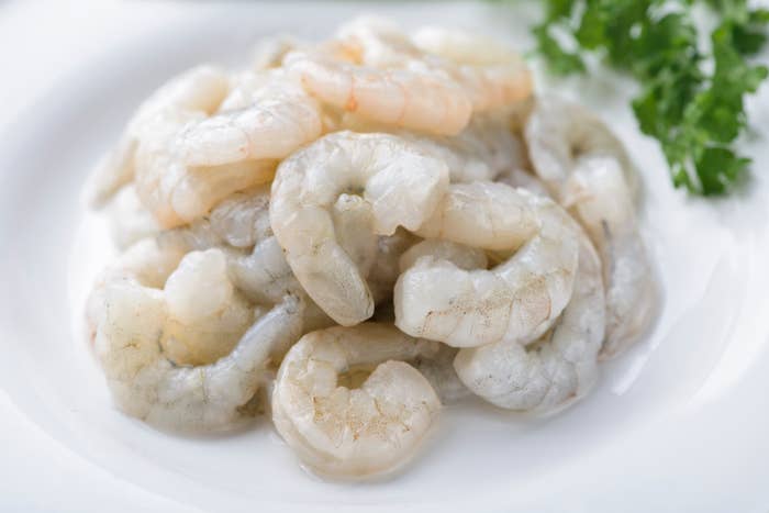 A sheet of uncooked shrimp heaped unneurotic with a sprig of parsley for garnish