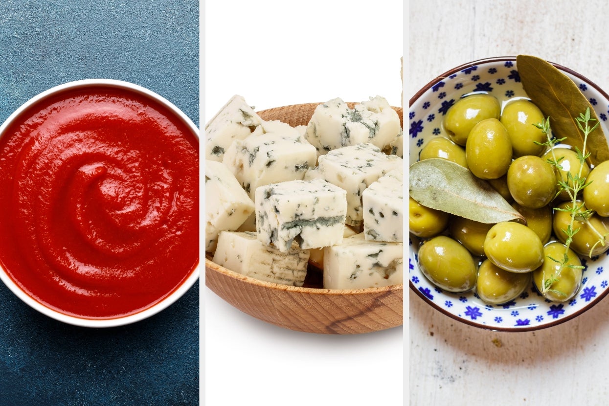 A bowl of tomato puree, a bowl of blue cheese cubes, and a bowl of green olives with leaves and herbs