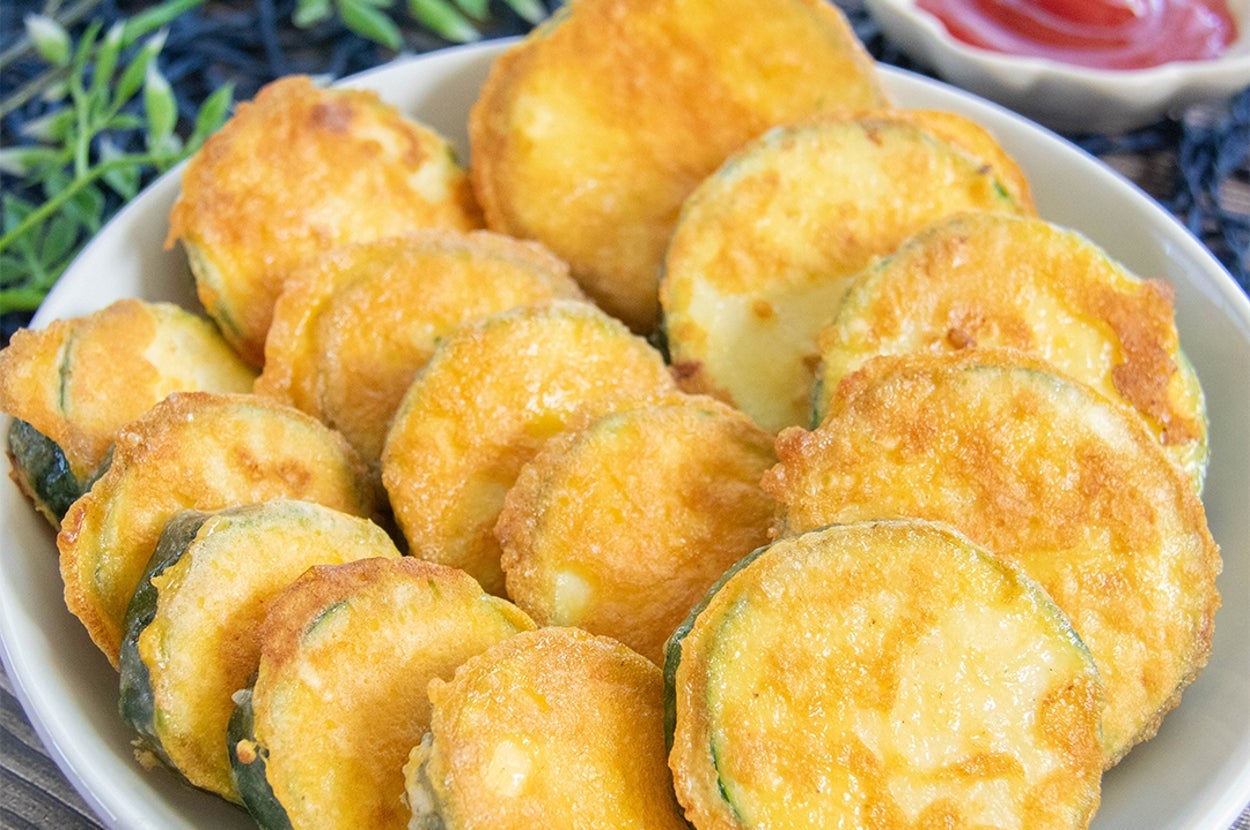 皿に並べられたズッキーニのピカタ。粉チーズと卵の衣を付けて焼いてある。トマトケチャップが添えられている。