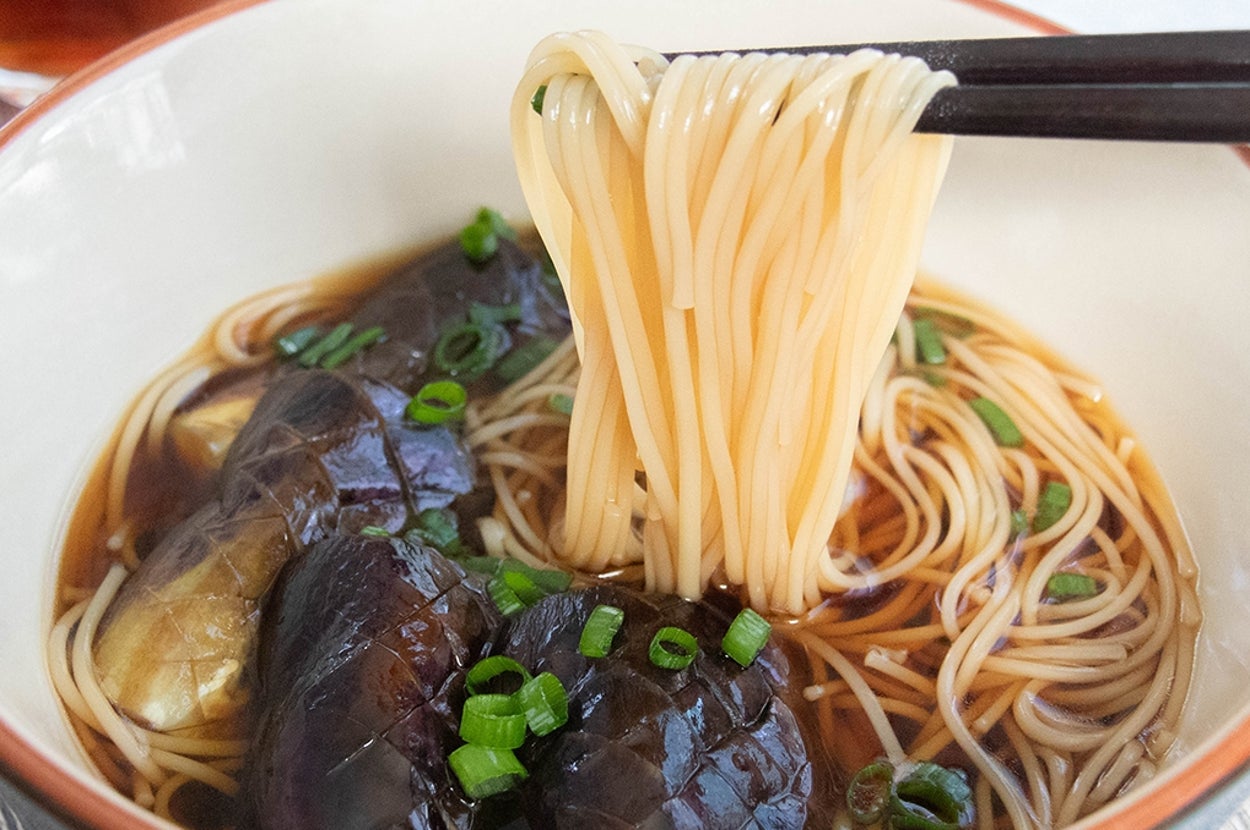 箸で持ち上げられたそうめん。丼には焼き浸しにしたなすが1本分入っている。