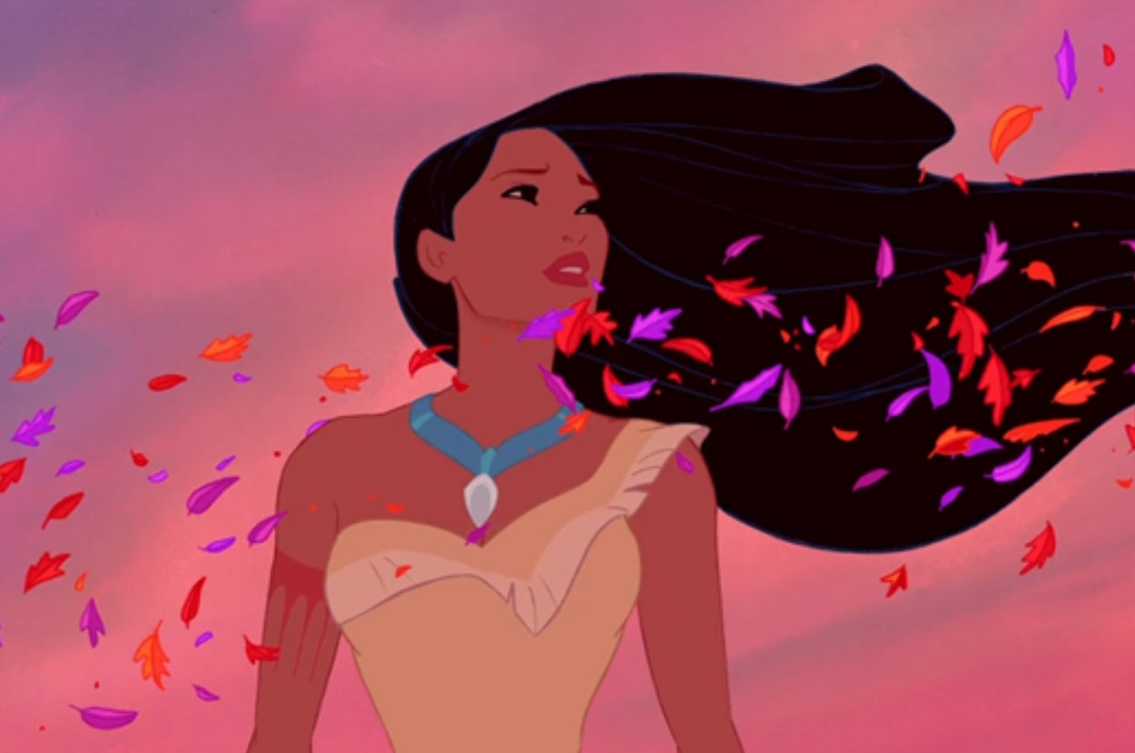 Animated character with long hair and a blue necklace stands outdoors surrounded by swirling leaves