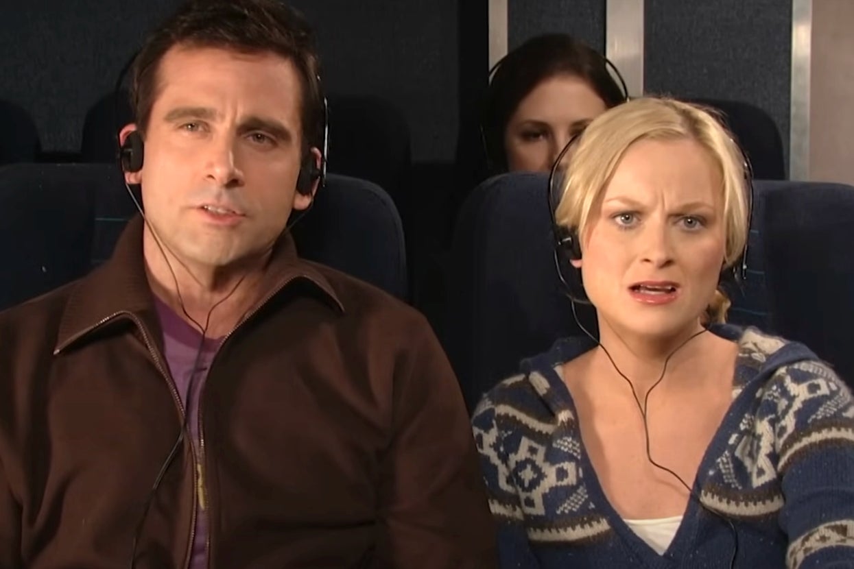 Two people wearing headphones are seated on an airplane, looking concerned