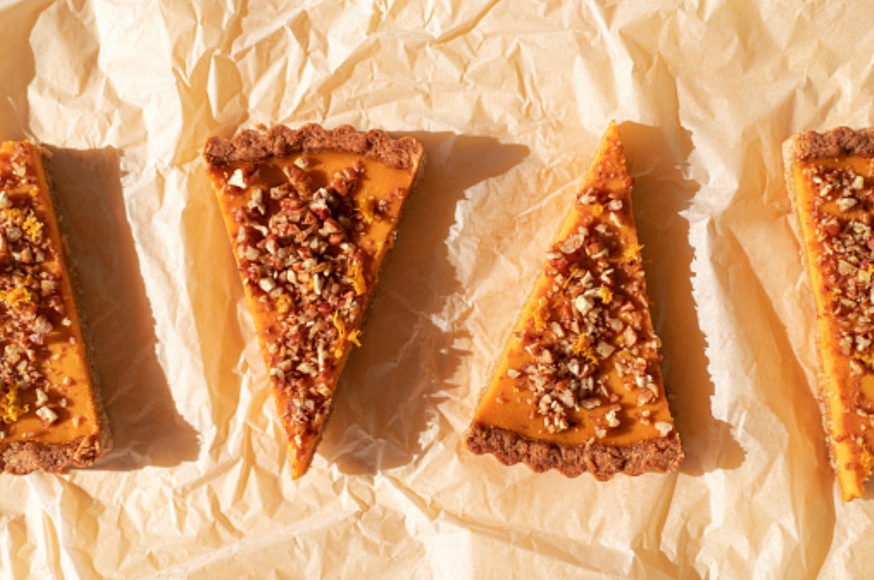 Four slices of pumpkin pie with nut topping on parchment paper