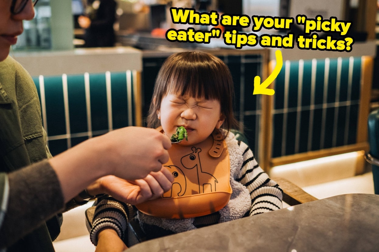 A child makes a funny face while being fed broccoli, wearing a bib with animal designs. Text asks for "picky eater" tips and tricks