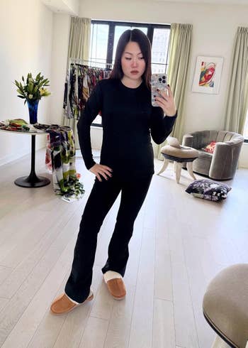 Person in a cozy outfit with slippers takes a mirror selfie.