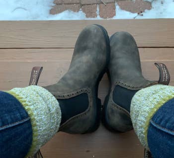 Brown boots with propulsion tabs shown connected a woody step, worn with yellow-knit socks and bluish jeans. Snow is disposable successful the background