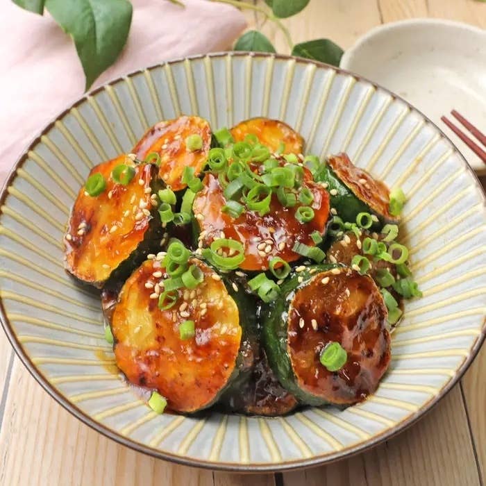 皿に盛られた照り焼き風の焼きズッキーニ、刻みネギとゴマがトッピング。