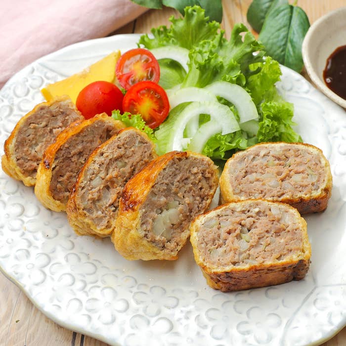 ミートローフ風の肉料理が皿に並び、レタス、トマト、玉ねぎのスライスが添えられている。