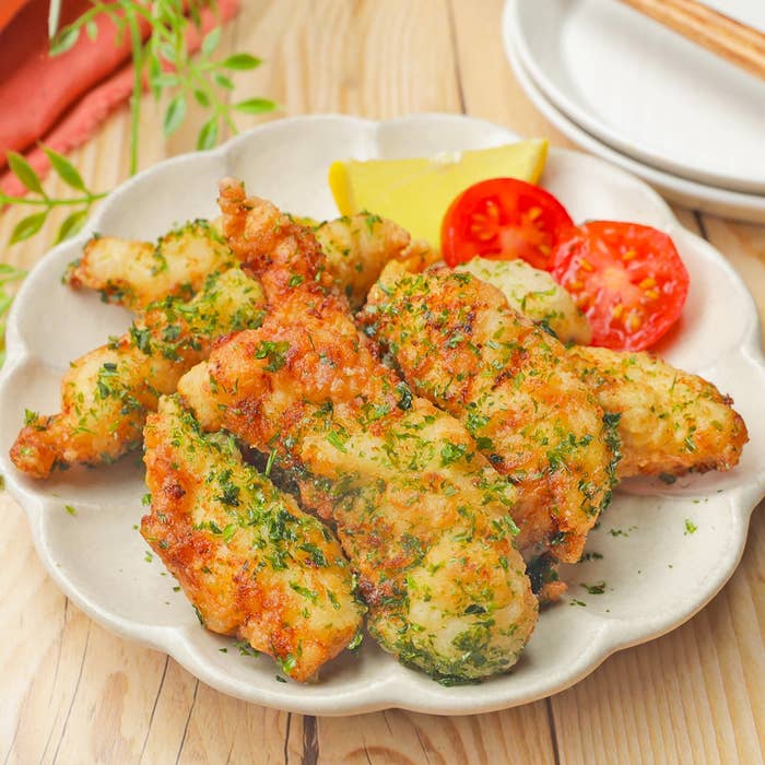 皿に盛られたフライドチキンとトマトのスライス、レモンのくさびが添えられている。