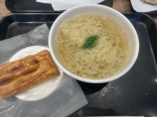 ラーメンの麺が入ったスープのボウルと、揚げ物が置かれたお皿がトレイに載っている。