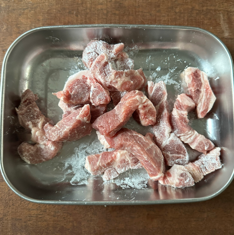 金属トレイに入った生の豚肉。切り分けられた状態で並べられている。