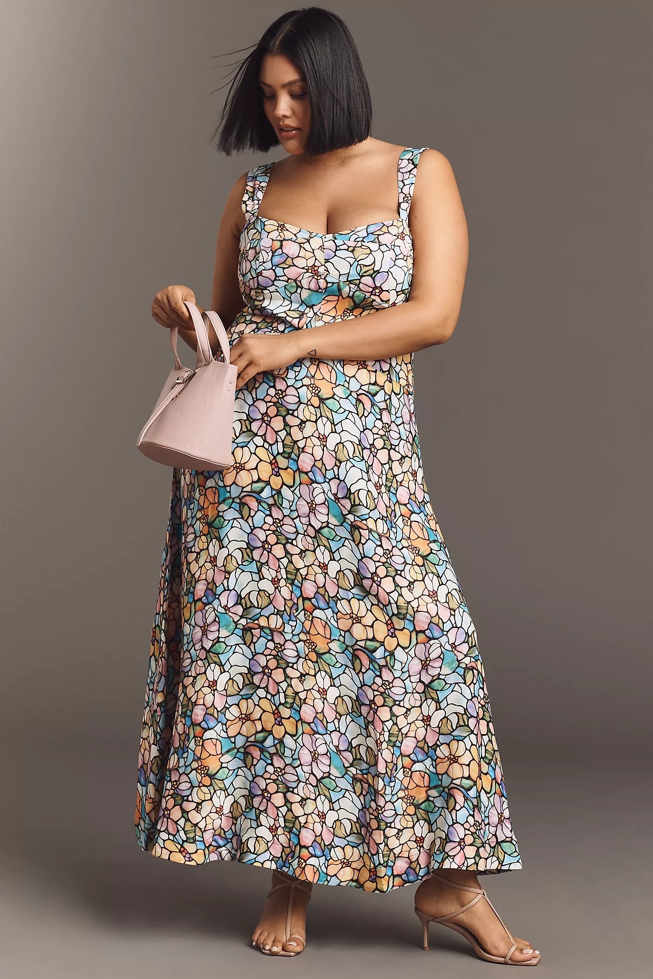 Person in a long, flowing floral dress holding a handbag, showcasing a casual yet elegant look suitable for shopping or casual events