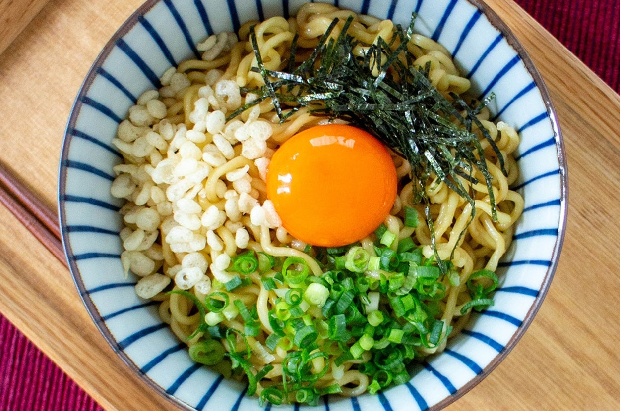 たっぷりの刻み海苔、卵黄、青ネギ、揚げ玉がトッピングされたラーメンのボウル。