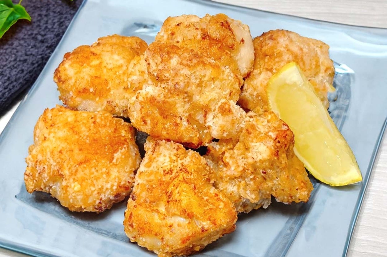 皿に盛られた揚げたチキンナゲットとレモンのくし形切り。