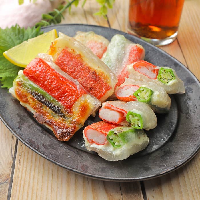 焼かれた餃子の盛り合わせが黒い皿に載っている。中に野菜とカニ風味の具が見え、隣に飲み物が置かれている。