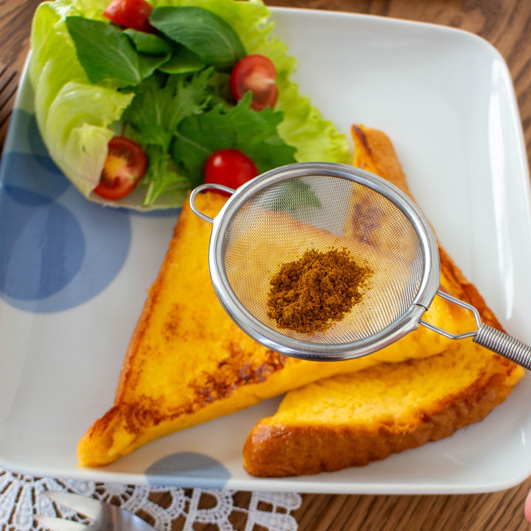 紅茶とパンのプレート。パンはカレー風味の粉がかかっており、付け合わせにレタスとプチトマトのサラダがある。