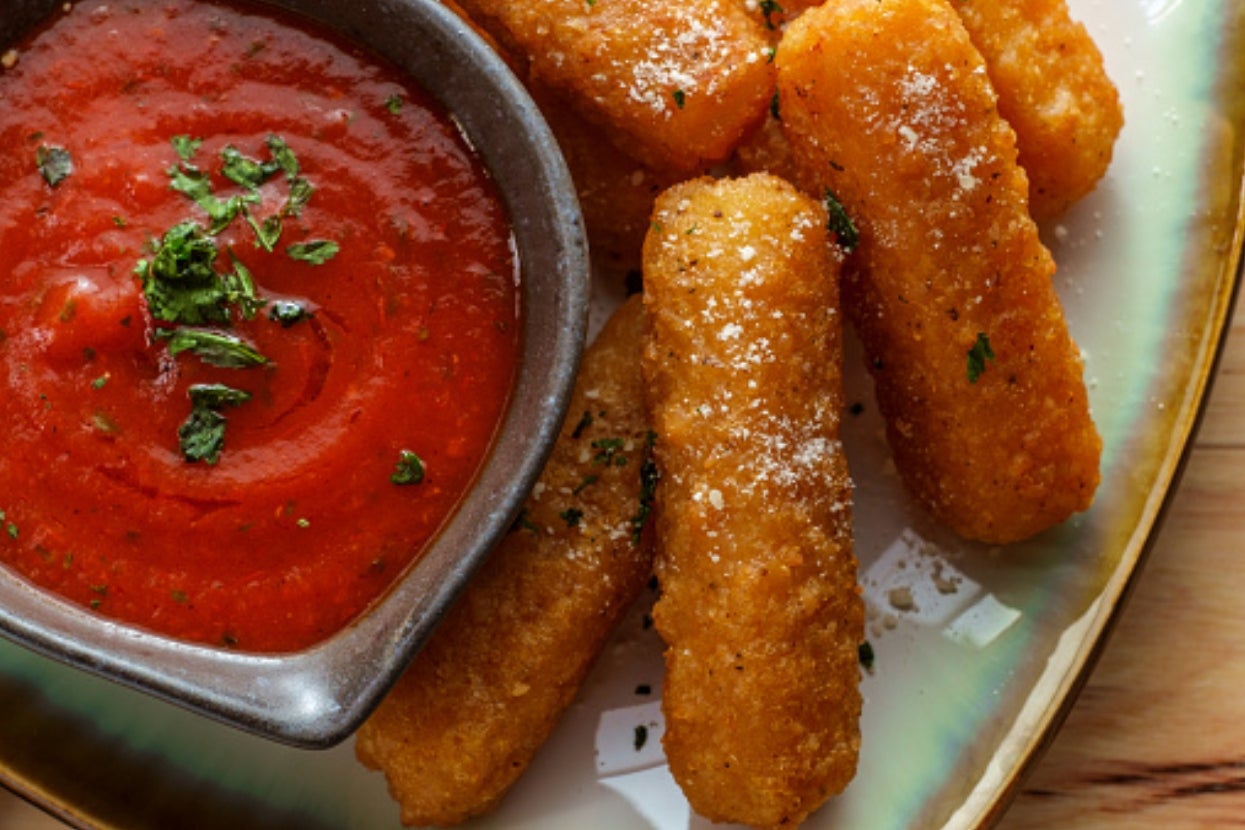 Mozzarella sticks on a plate with marinara sauce, garnished with herbs