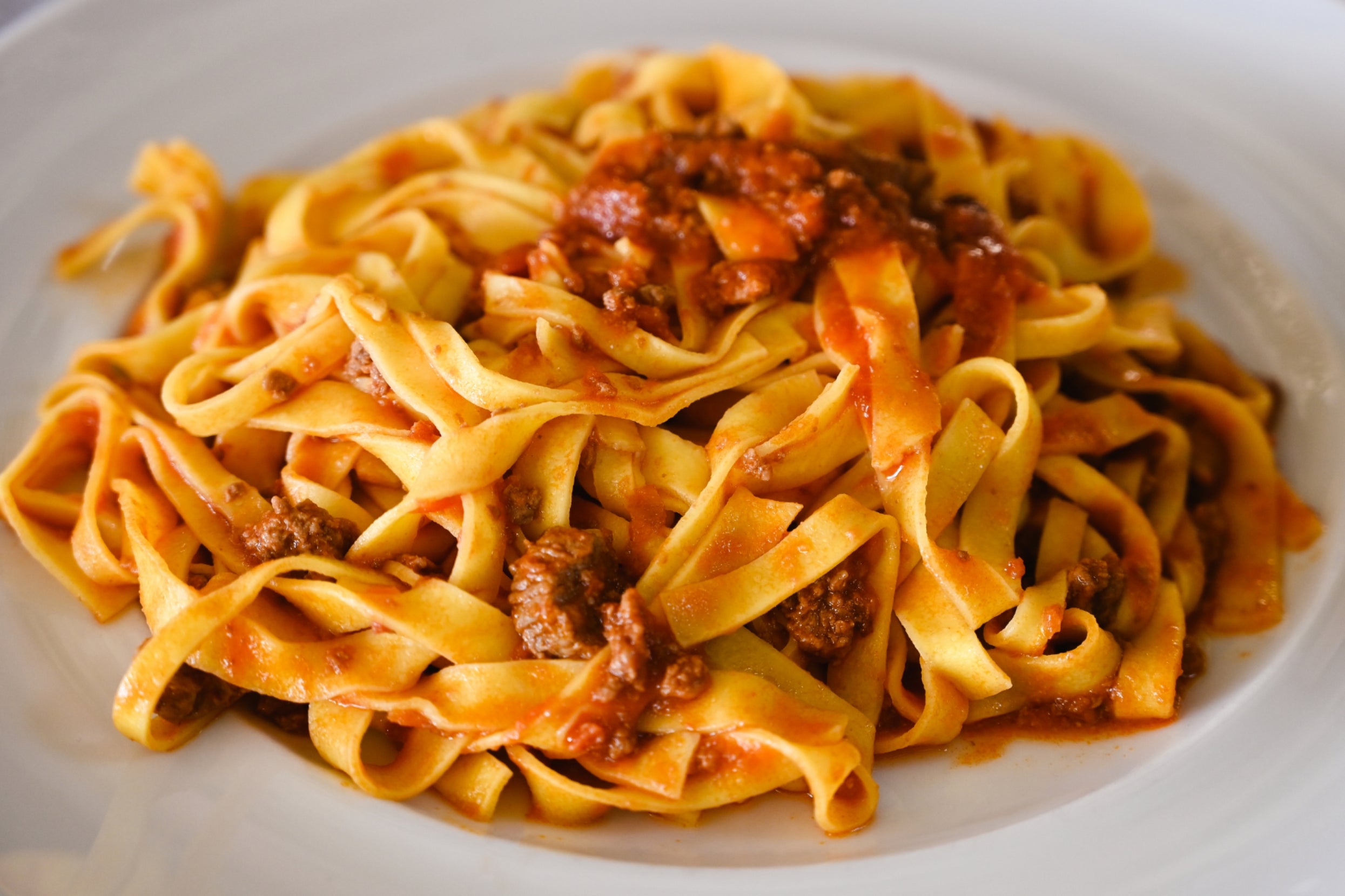 A plate of tagliatelle pasta with rich, savory meat sauce