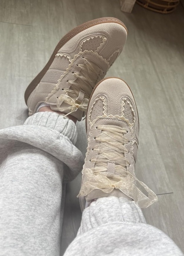 Person wearing stylish sneakers with lace details. The shoes have a unique textured design, paired with cozy sweatpants, suggesting comfort and style