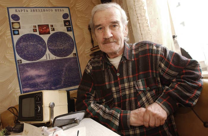 Man sitting successful a country with a prima representation down him, wearing a plaid shirt, adjacent to retro tech equipment