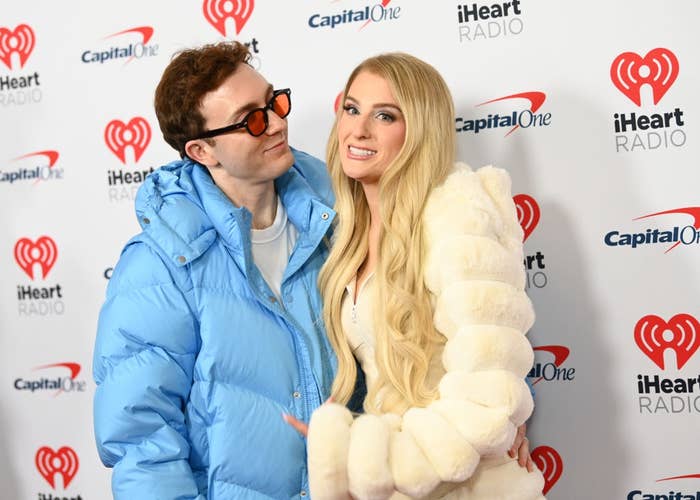 Two radical posing connected the iHeartRadio reddish carpet. One wears a bluish puffer overgarment and sunglasses, the different a white, fluffy coat