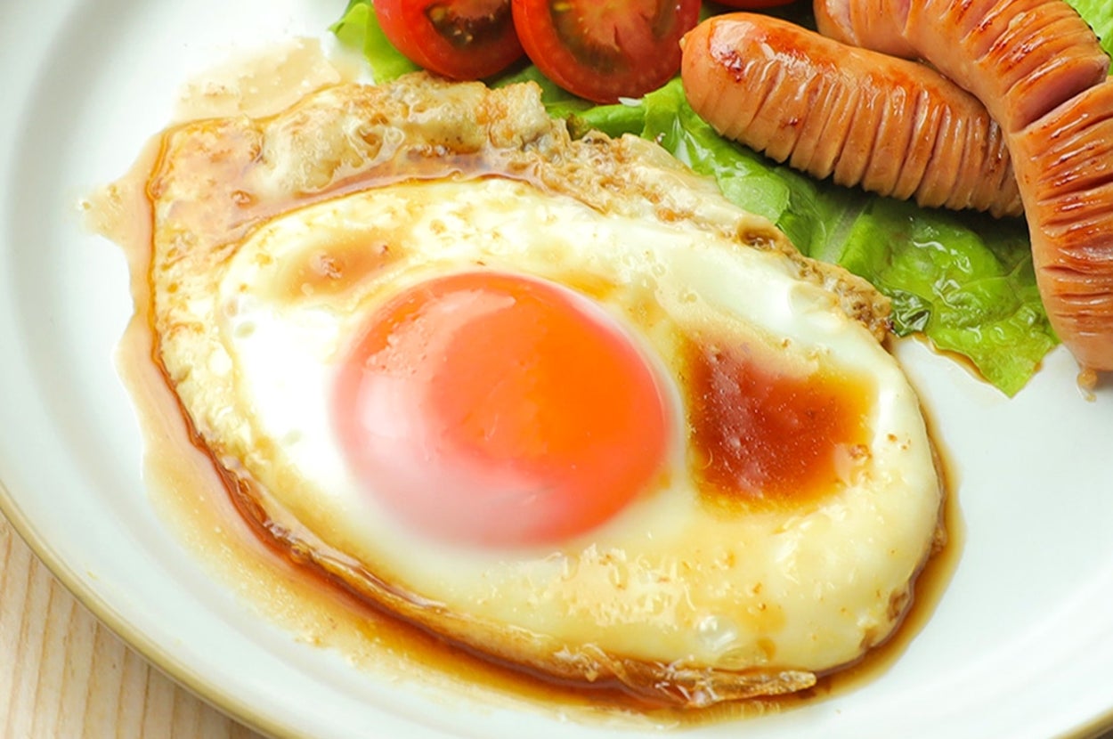 皿に盛られた目玉焼き、ソーセージ、レタス、トマト。