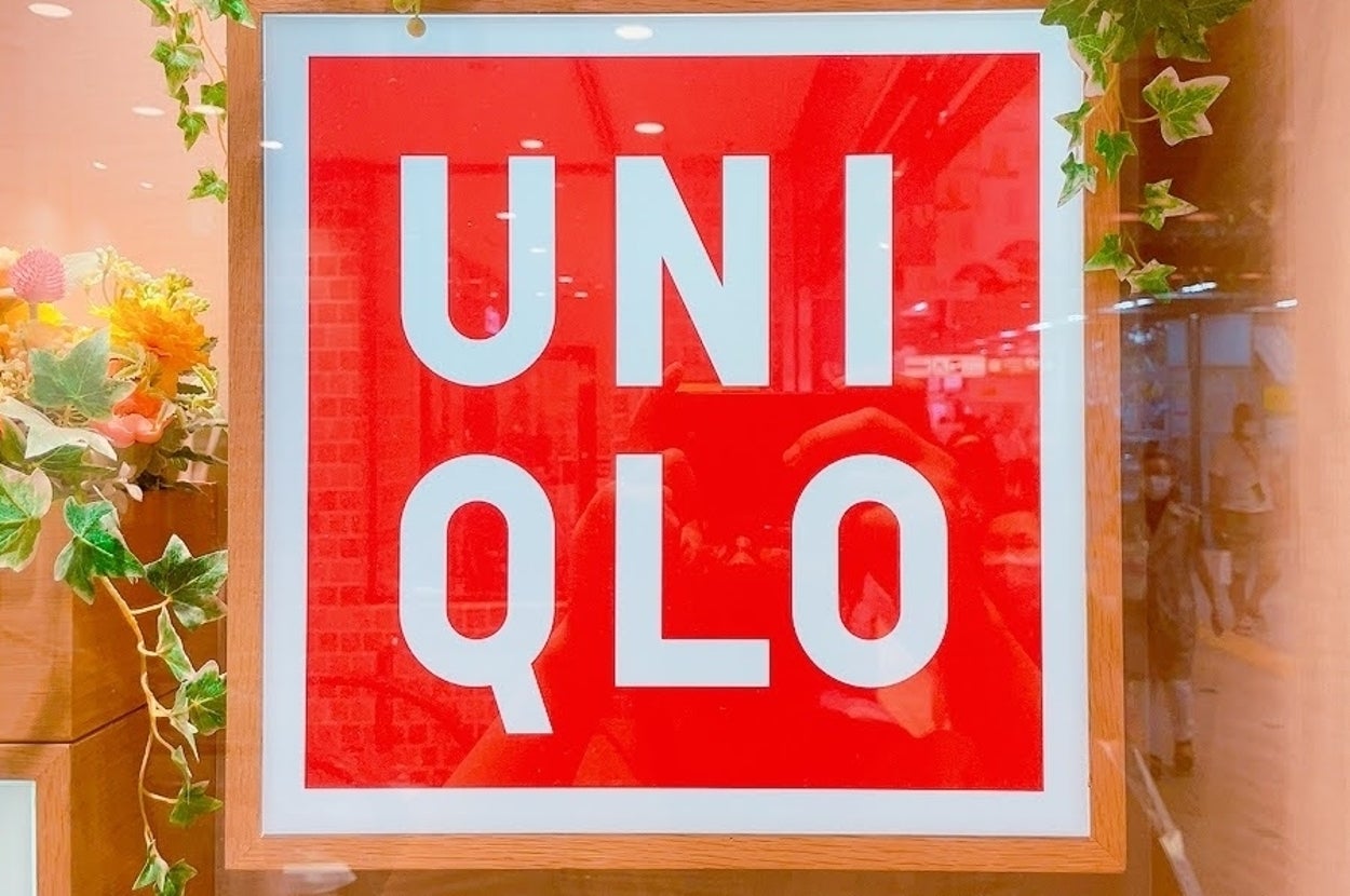 Red UNIQLO sign adorned with decorative greenery and flowers in a store setting