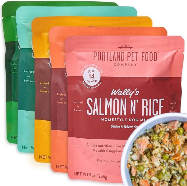 Four bags of Portland Pet Food Company dog meals with assorted flavors, next to a bowl of mixed dog food