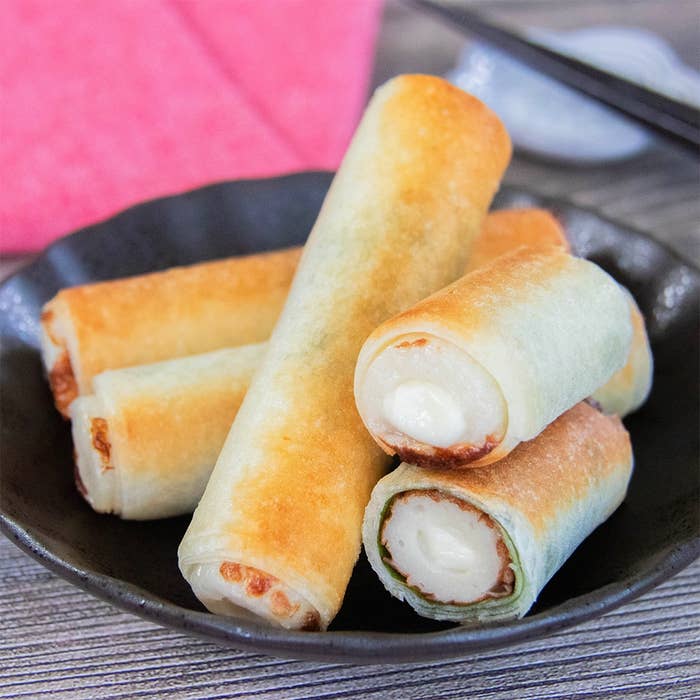 黒い皿に盛られたチーズ入りちくわを春巻きの皮で巻いて焼いた料理がテーブルに置かれている。