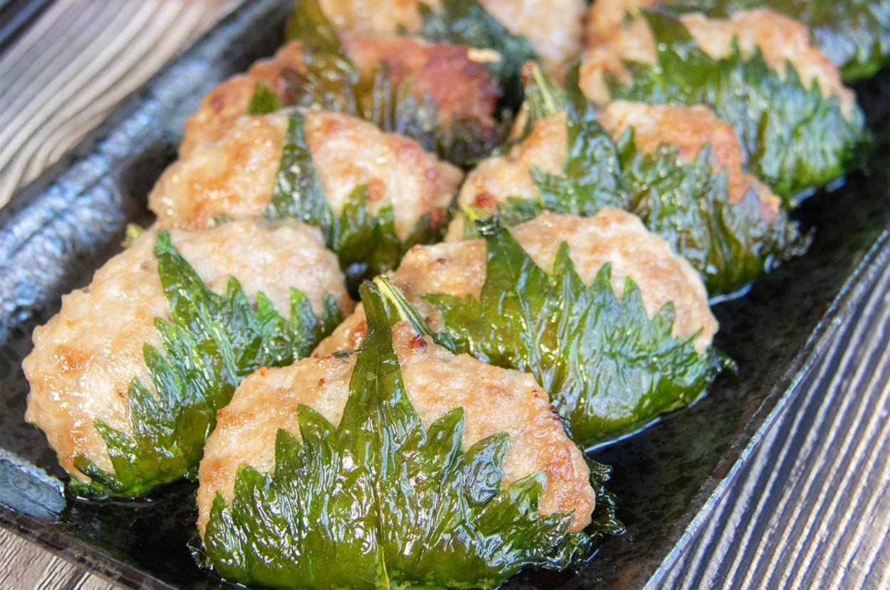 皿に盛られた大葉に包まれた肉団子料理が並ぶ。左上にたれの小皿が置かれている。