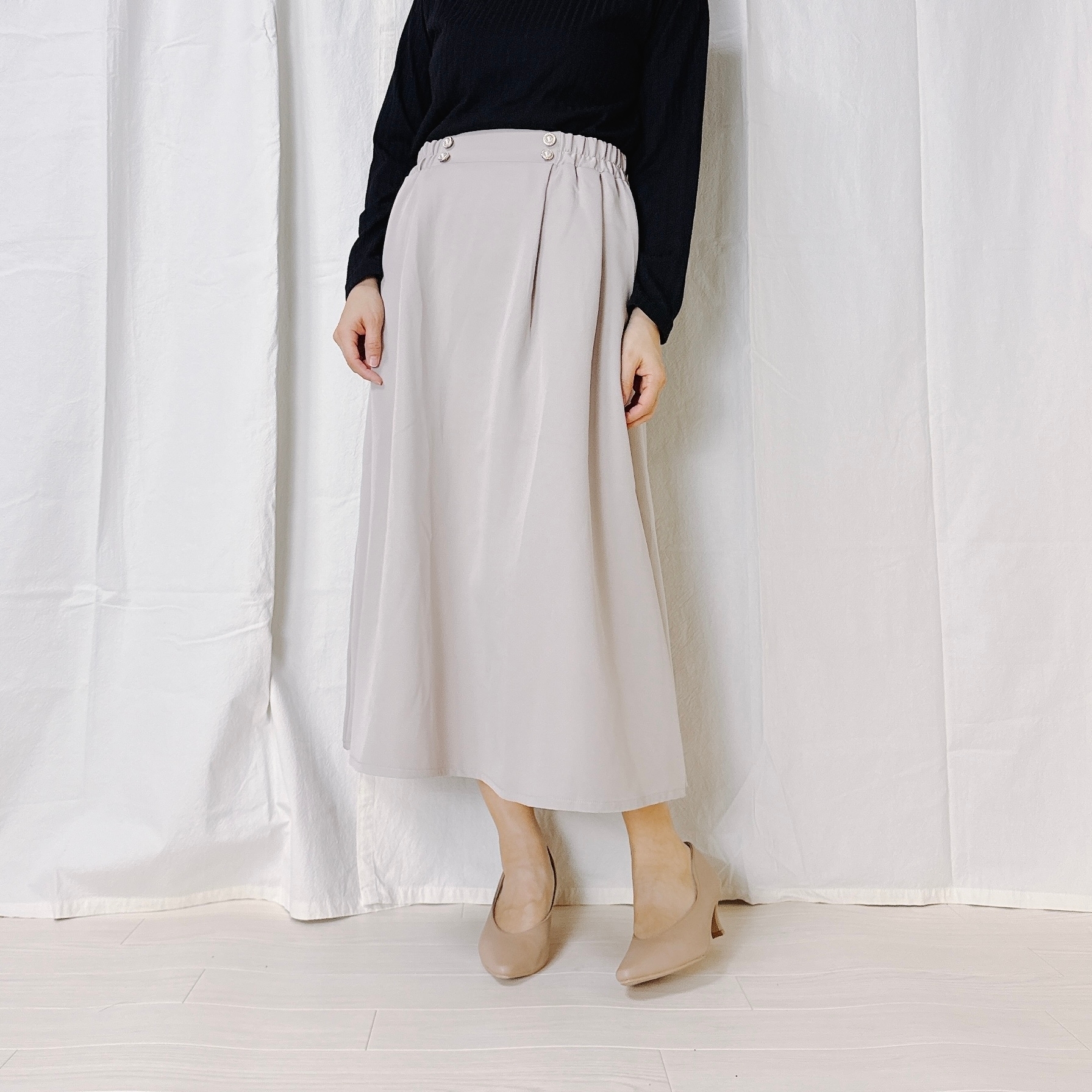 女性がシンプルなロングスカートとプルオーバーの服装で立っている。ワイドカットのスカートデザイン。
