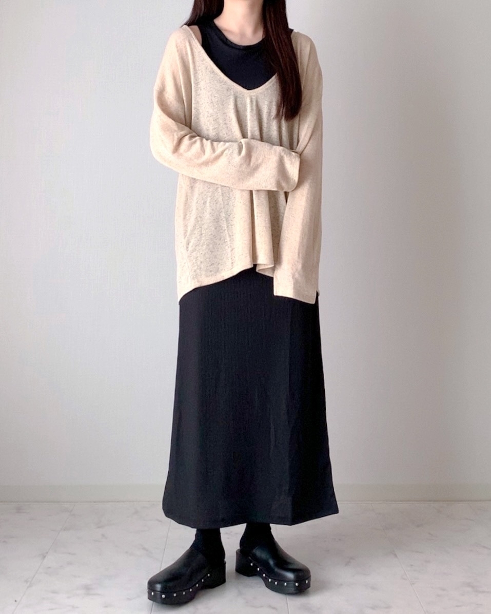 ゆったりしたニットと長い黒のワンピースを着た人物。シンプルでカジュアルなスタイル。